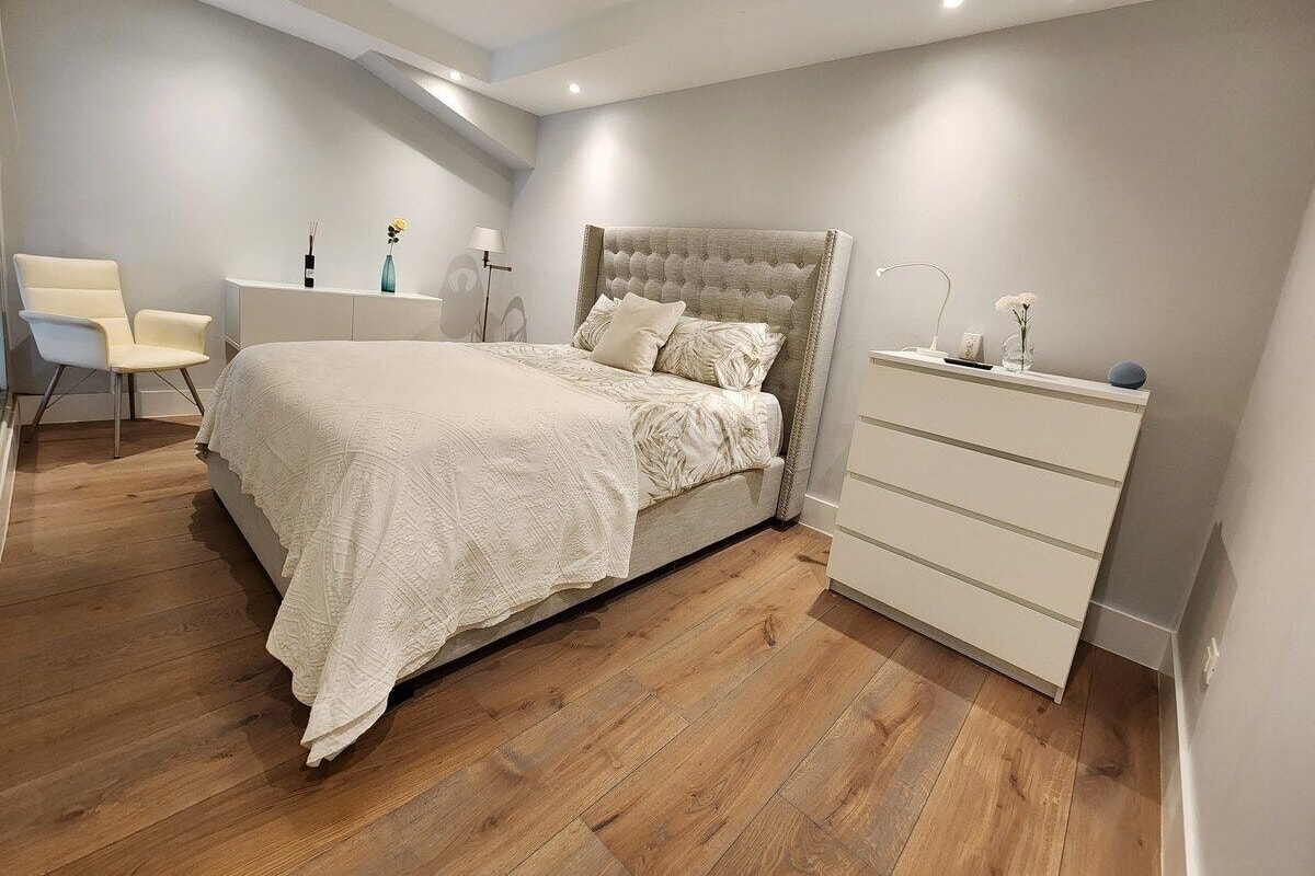 A bedroom with a bed, bedside table, dresser, and a chair.