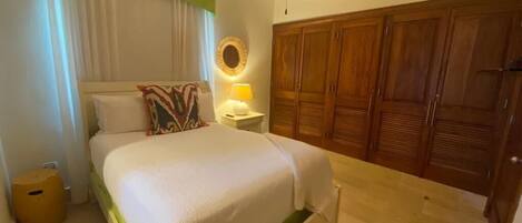 A bedroom with a bed, a nightstand, a lamp, a ceiling fan, and a wardrobe.