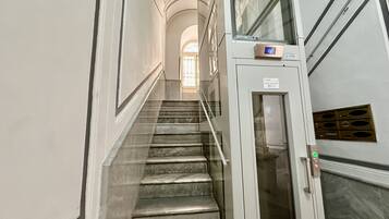 A staircase leading to an elevator in a building with white walls and a marble floor.