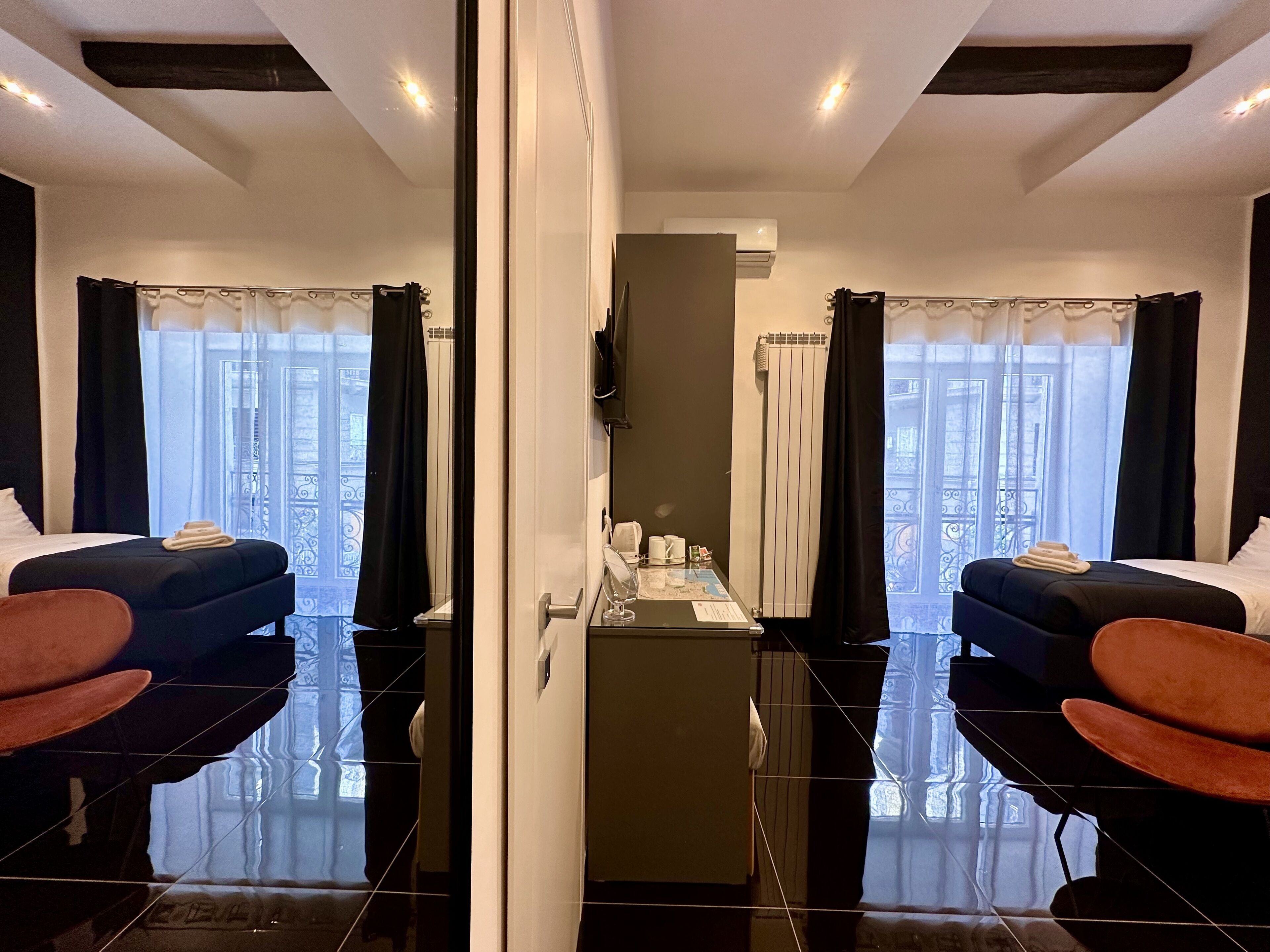 Ein Hotelzimmer mit einem großen Spiegel, zwei Betten, einem kleinen Tisch mit einer Karte und Blick auf den Balkon.
