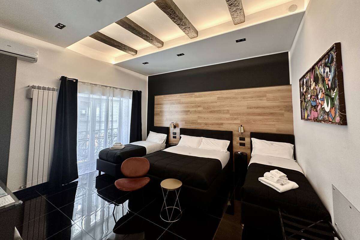 Une chambre d’hôtel moderne équipée d’un grand lit, d’un lit plus petit, d’un bureau et d’une chaise.