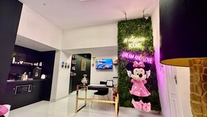 A modern interior with a neon sign, a plush Minnie Mouse decoration, and a green wall. - Elegance Rooms Spaccanapoli (Naples)