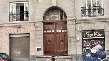 Ein Gebäude mit einer großen Holztür, einem Schild mit der Aufschrift 'Six One Clothing' und zwei Mülltonnen auf dem Bürgersteig.