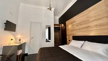 A modern bedroom with a large bed, a desk with a mirror, and a TV mounted on the wall.