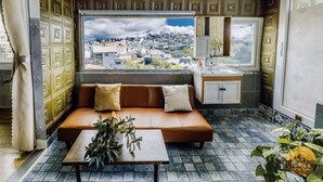 A cozy room with a sofa, a small table with a plant, a window with a city view, and a sink. - Mây's House (Xuan Huong - Da Lat)