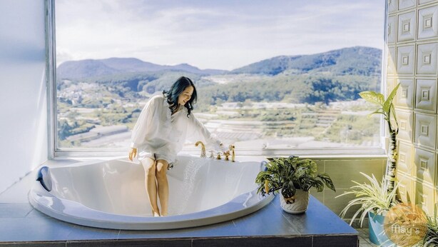 A person in a bathtub with a scenic view of mountains and fields. - Mây's House (Xuan Huong - Da Lat)