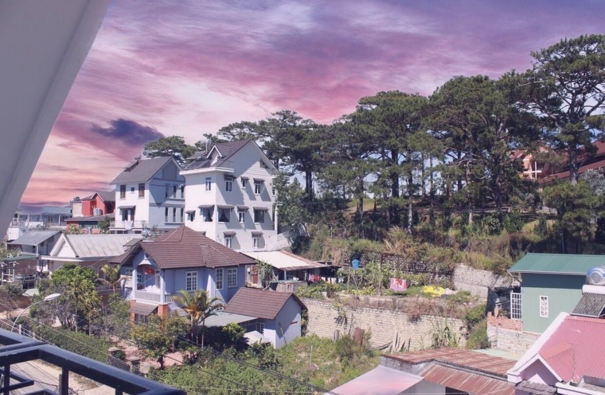 A residential area with houses, trees, and a hillside.