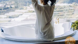A person in a bathtub with a view of mountains and a cityscape. - Mây's House (Xuan Huong - Da Lat)