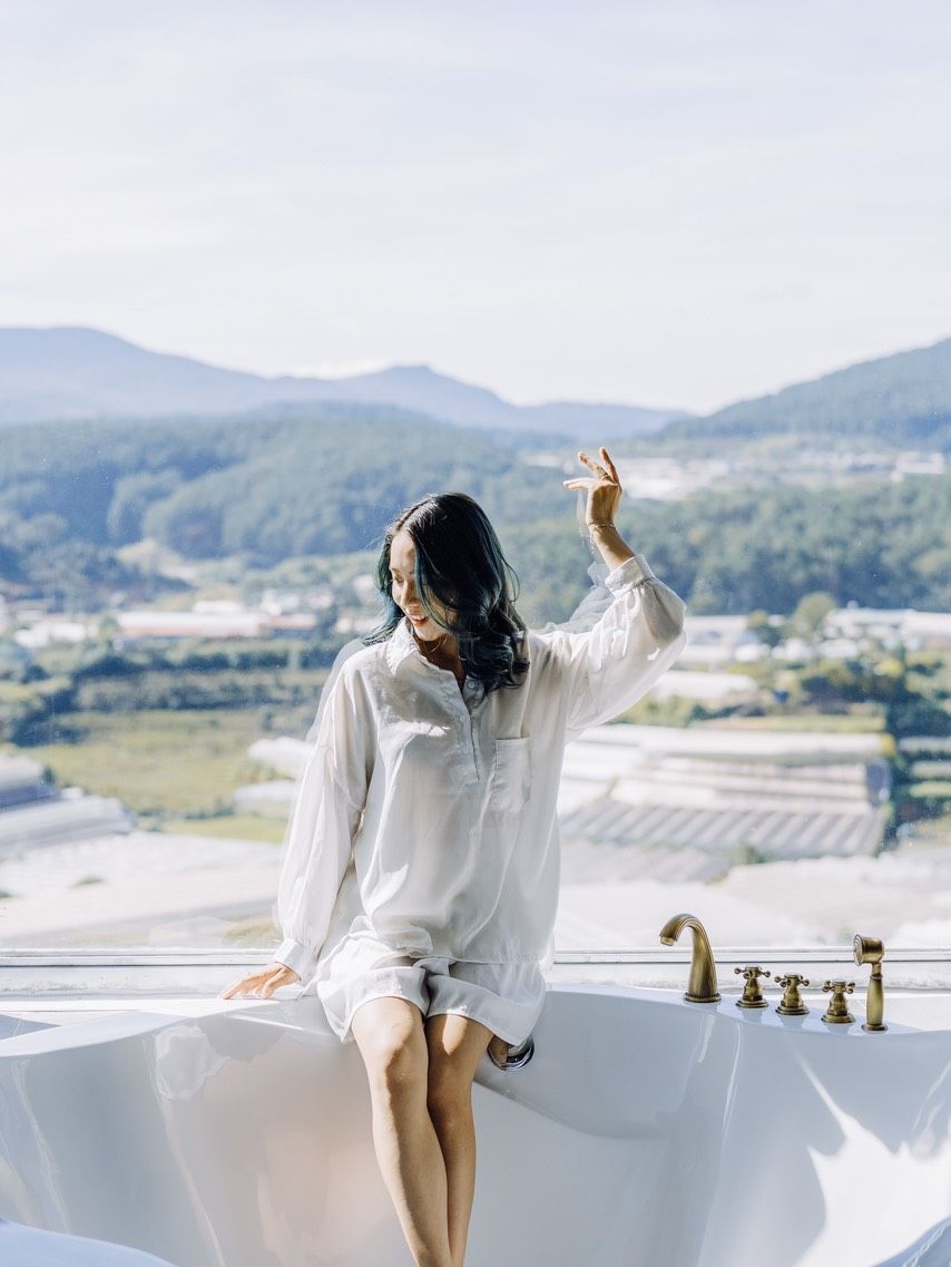 Une personne assise dans une baignoire, avec vue sur un paysage.