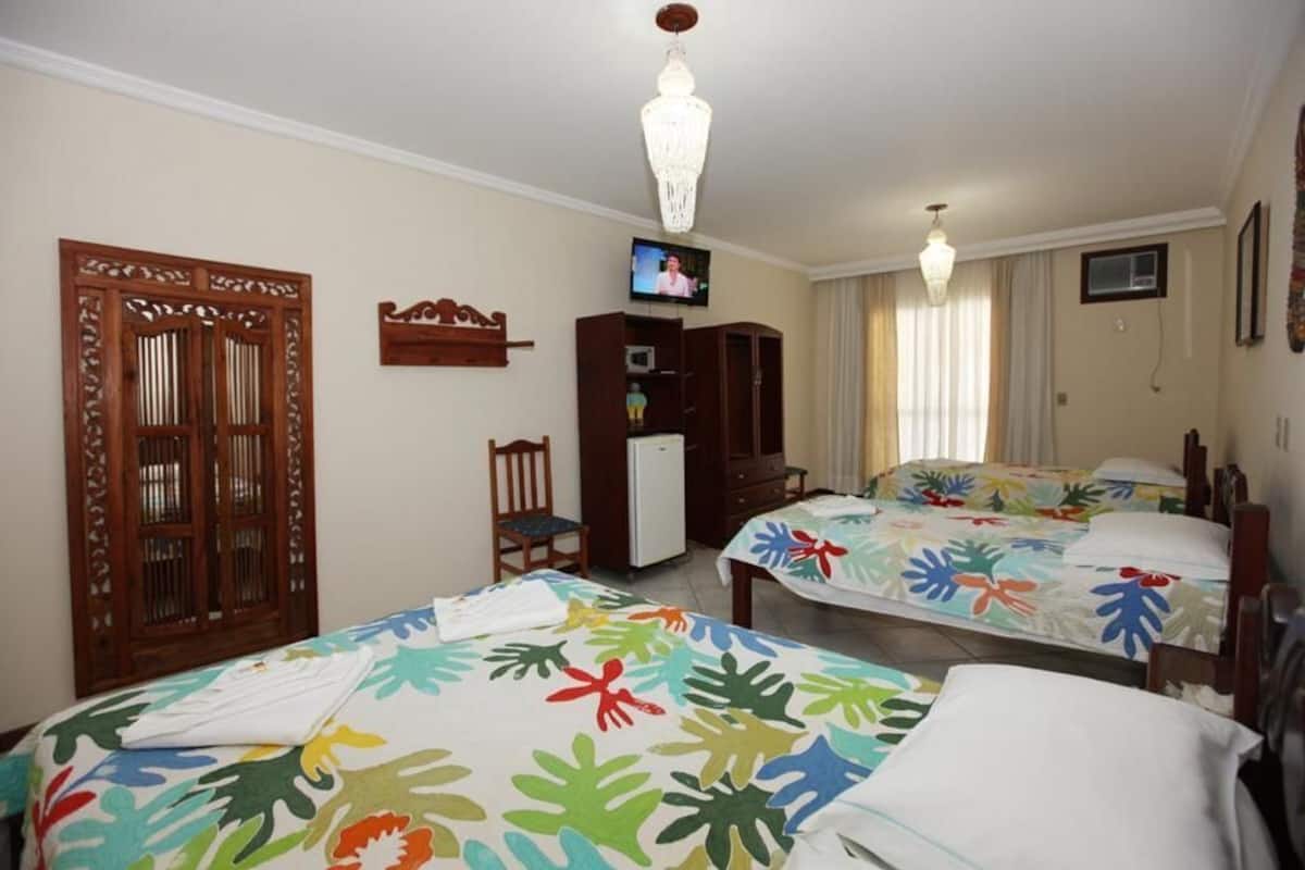 A hotel room with two beds, a television, a wardrobe, and a small desk.