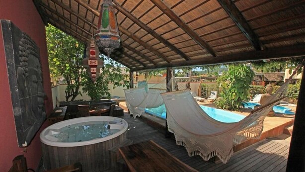 A wooden deck with a hot tub, hammocks, and a pool area. - Hotel Kima (Bombinhas)