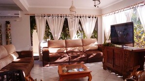 A living room with a brown sofa, a wooden coffee table, a TV, and a cabinet. - Hotel Kima (Bombinhas)