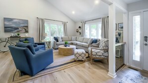 Ein modernes Wohnzimmer mit einer Couch, Sesseln, einem Couchtisch und einem gemusterten Sessel.