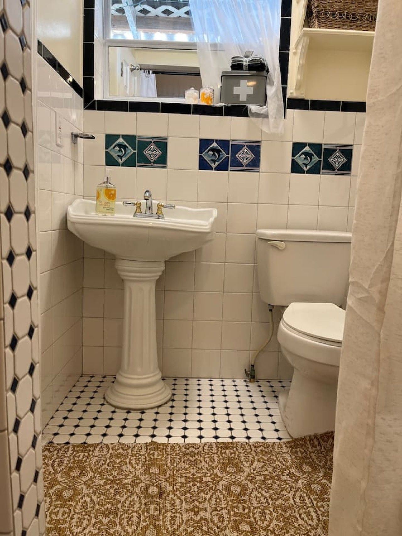 A bathroom with a pedestal sink, toilet, and patterned floor tiles.