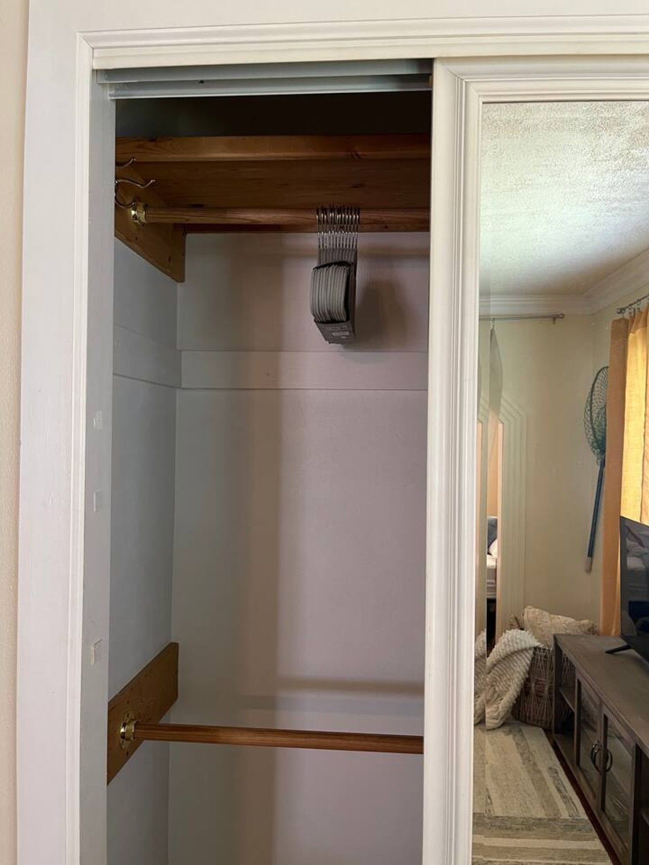 Un armario con barra de madera y ropa colgada.