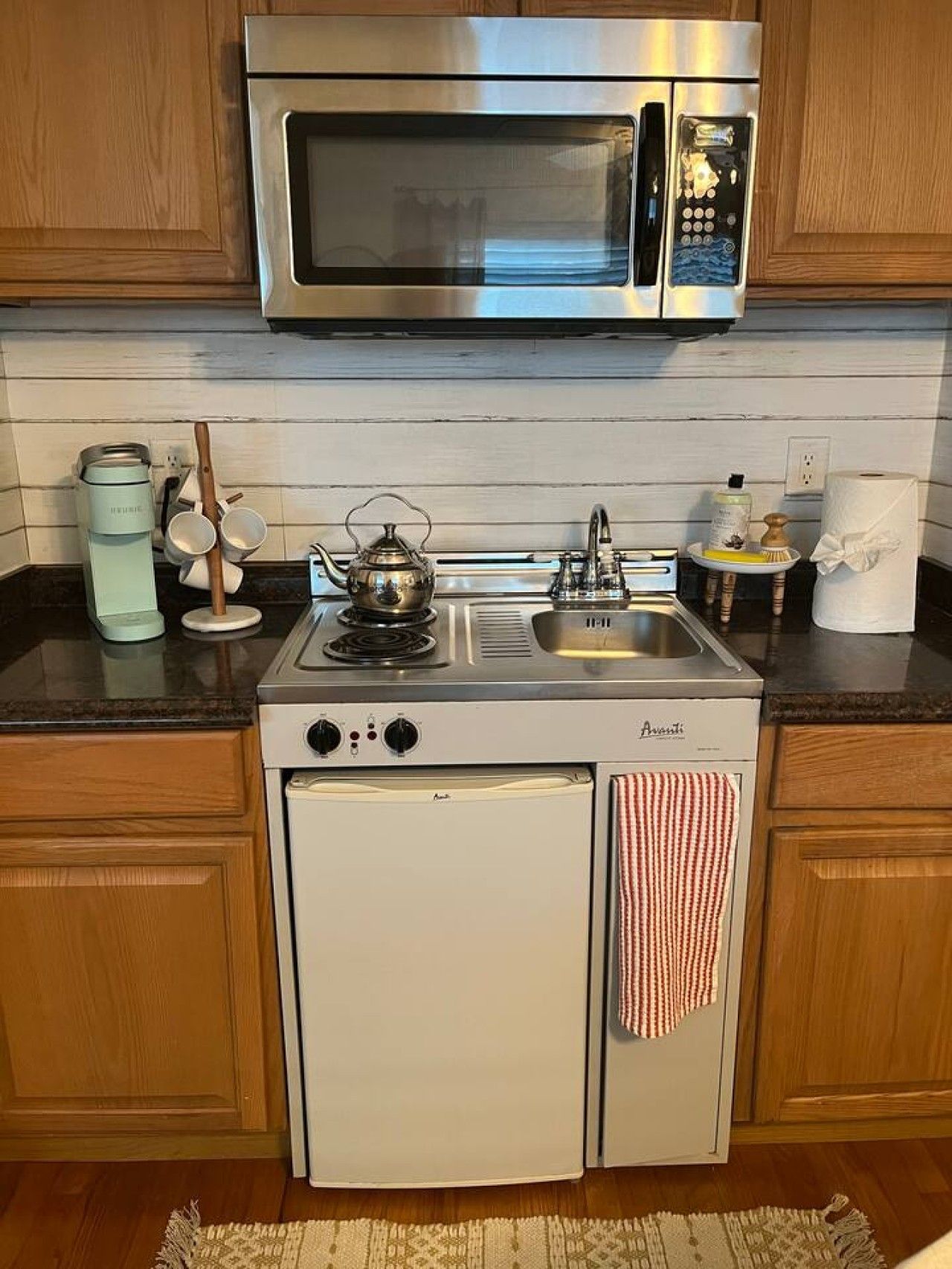 A compact kitchen with a built-in microwave, a stovetop, and a mini refrigerator.