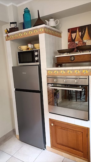 Uma cozinha compacta com geladeira de aço inoxidável, micro-ondas e forno embutido.