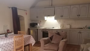 A compact kitchen with white cabinets, a dining table with chairs, and a sofa. - Stunning 2-bed Apartment in Carlow Town (Carlow)