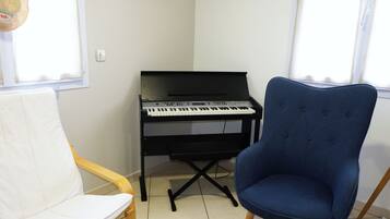 Una habitación con un piano, una silla blanca acolchada y una butaca azul tapizada.