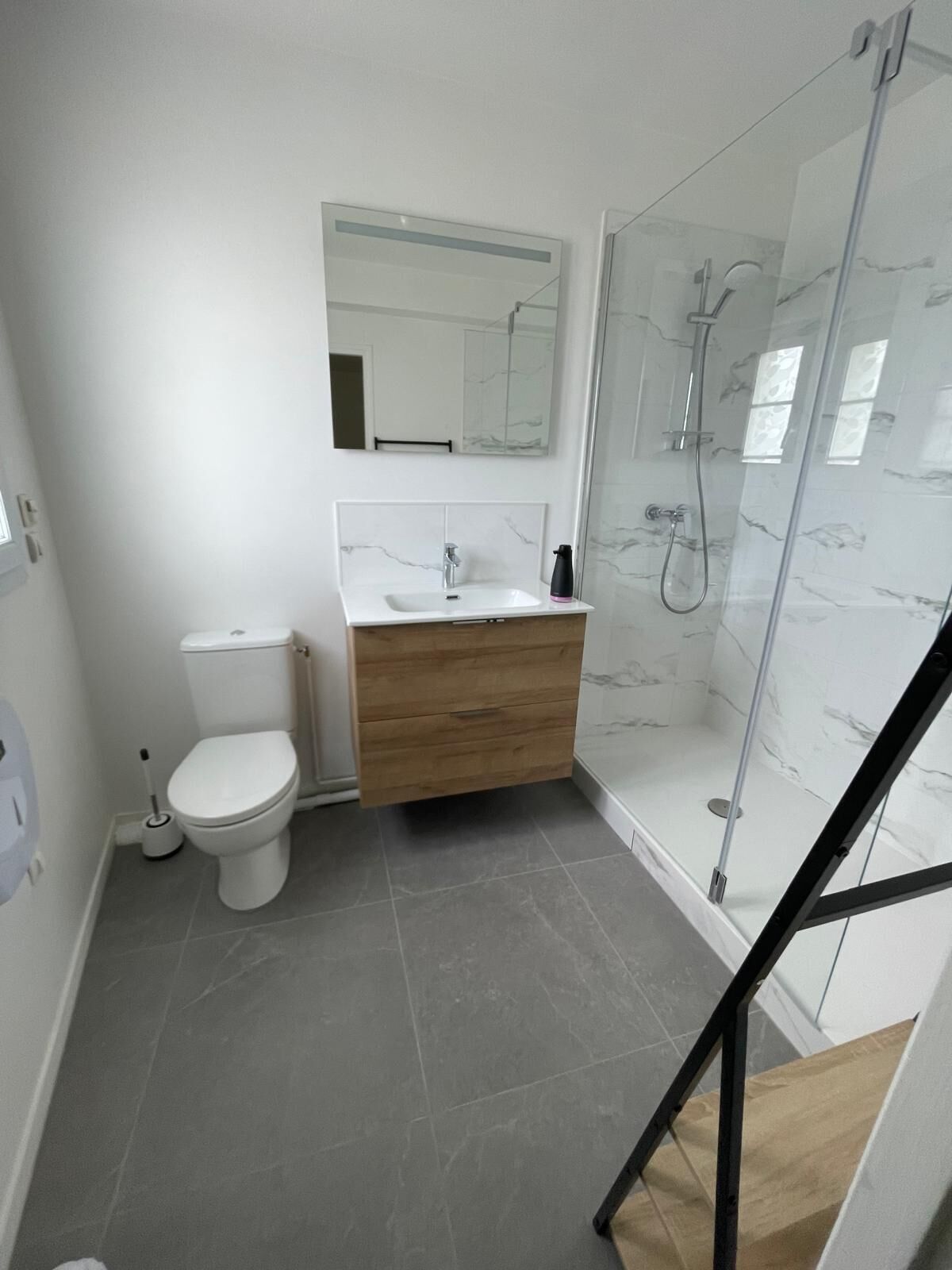 A modern bathroom with a toilet, sink, and glass shower enclosure.