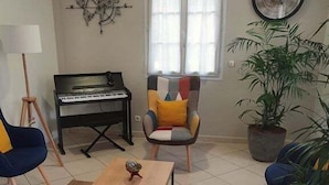 Un salon avec un piano, un fauteuil moderne, une table basse et une plante en pot.
