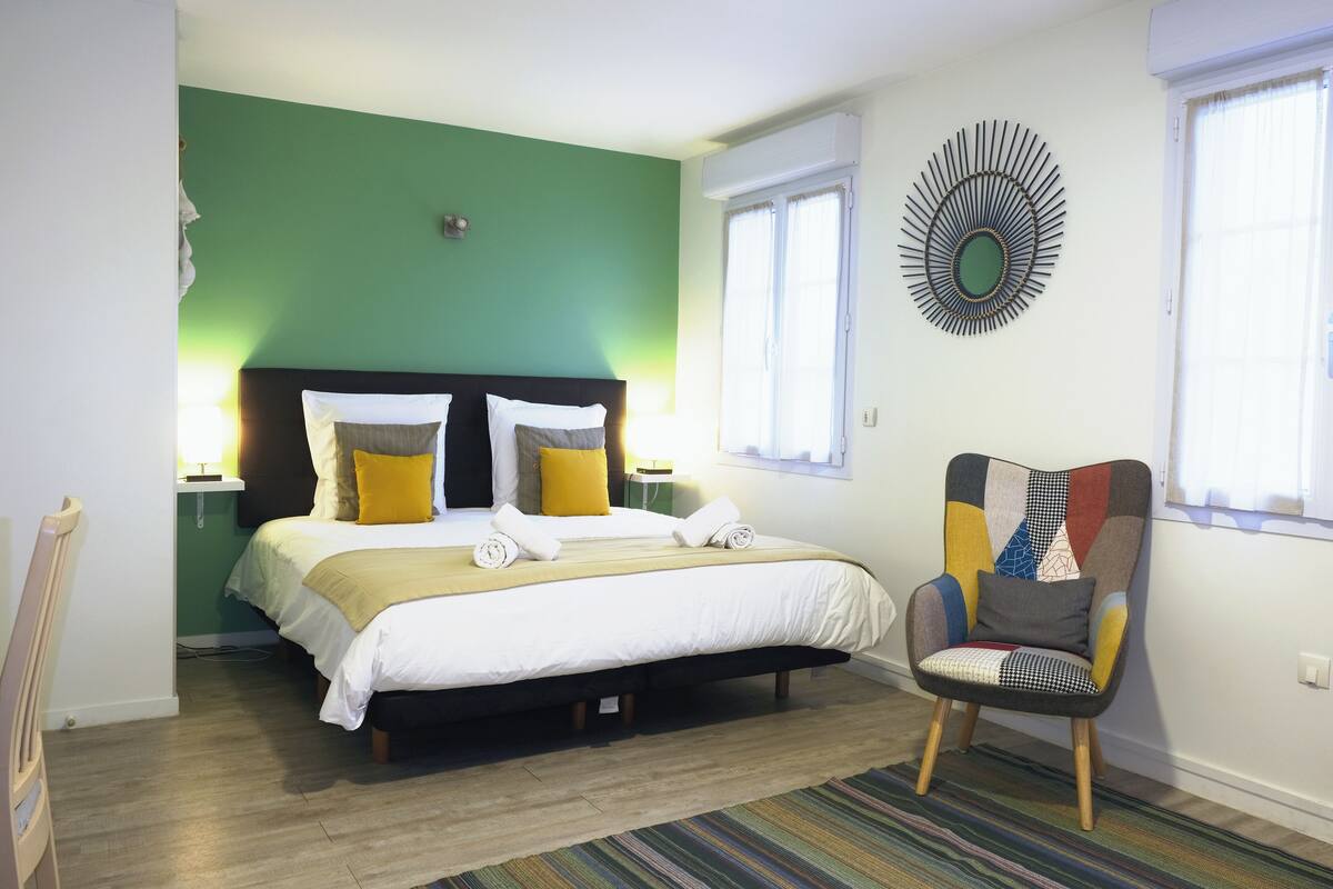 A bedroom with a bed, a chair, and a wall decoration.