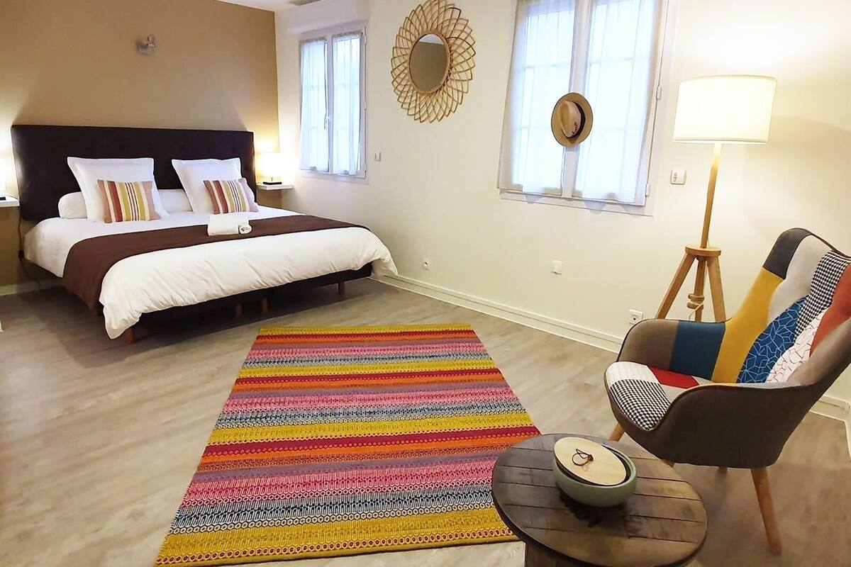 A bedroom with a bed, a colorful rug, a chair, and a lamp.