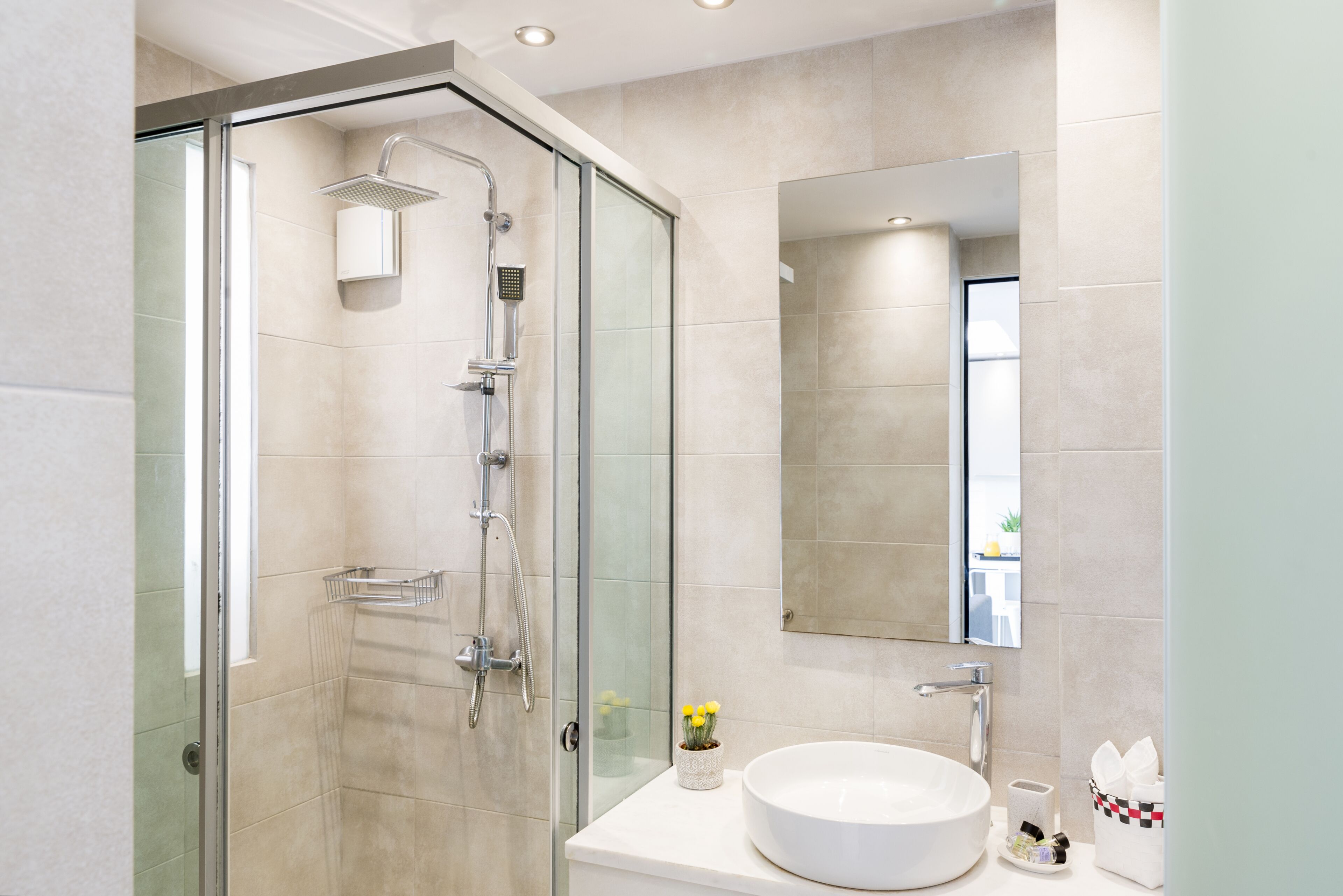 A modern bathroom with a glass-enclosed shower, a round sink, and a large mirror.