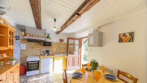 A kitchen with wooden cabinets, a microwave, and a sink. There is a dining table with plates and a vase of flowers.