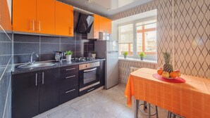 Een moderne keuken met zwarte en oranje kastjes, een roestvrijstalen gootsteen en een raam met uitzicht.