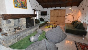 A cozy living room with a stone fireplace, green sofa, and a wooden cabinet. - RUSTIC BELLAVISTA (Caneggio)