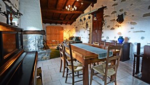 A rustic dining area with a wooden table and chairs, stone walls, and a chandelier. - RUSTIC BELLAVISTA (Caneggio)