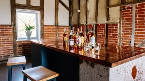 Un espace bar agrémenté d’un mur en briques rustiques, de poutres en bois et d’une variété de bouteilles d’alcool.