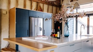 Une cuisine moderne avec un îlot central en bois, des appareils électroménagers en acier inoxydable et un vase rempli de fleurs.