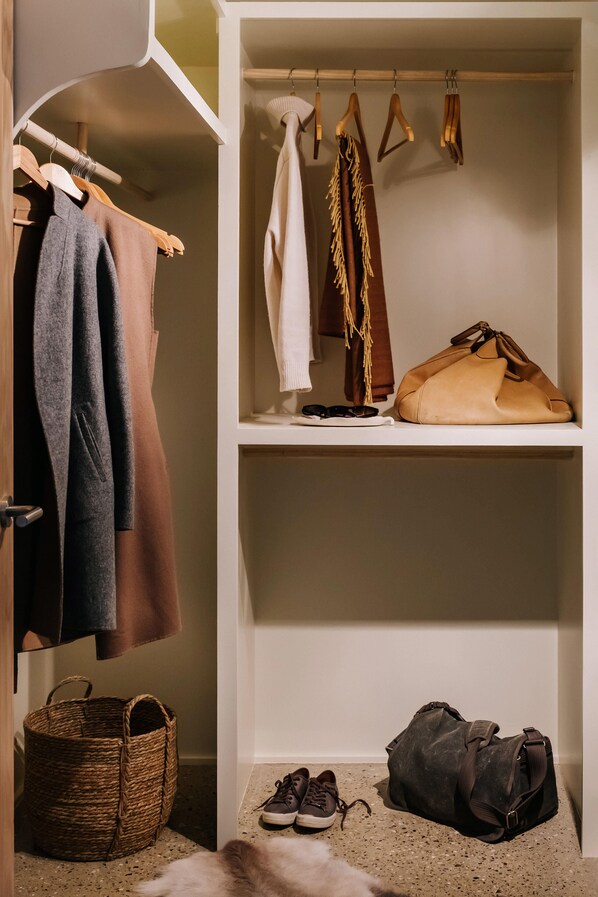 Un vestidor amplio con ropa colgada, estantes con bolsos, una cesta y zapatos.