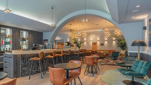 Un'area bar moderna con un bancone in marmo, poltrone in pelle e una selezione di bottiglie.