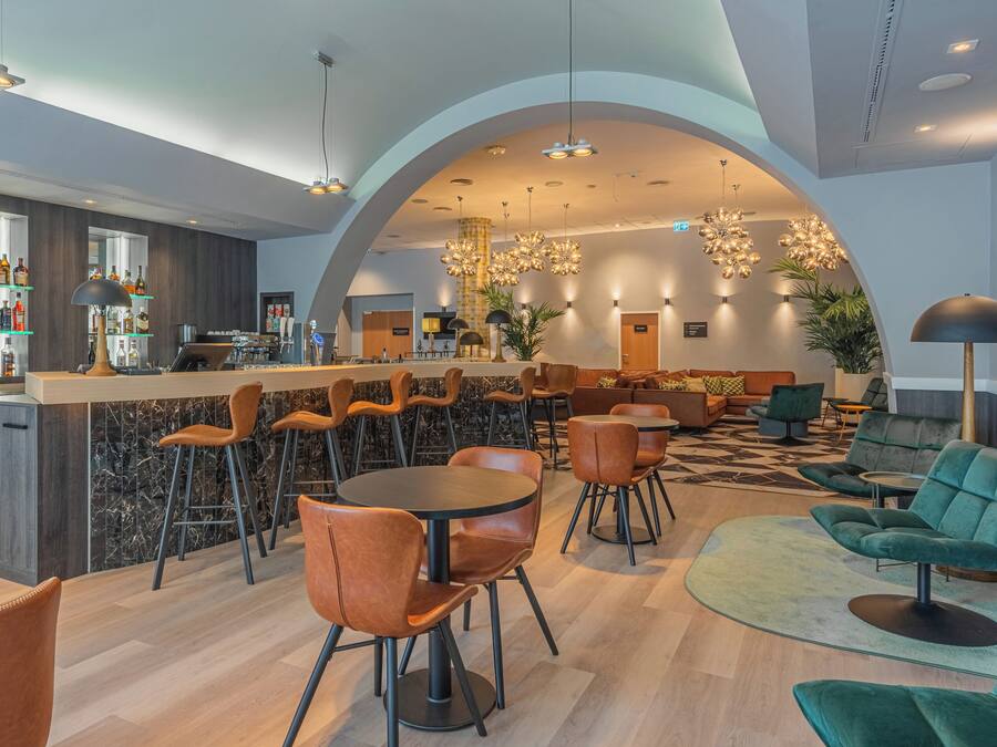 Un espace bar moderne avec un comptoir en marbre, des fauteuils en cuir et un assortiment de bouteilles.