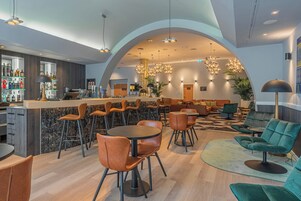 Um espaço de bar moderno com balcão de mármore, cadeiras de couro e diversas garrafas.