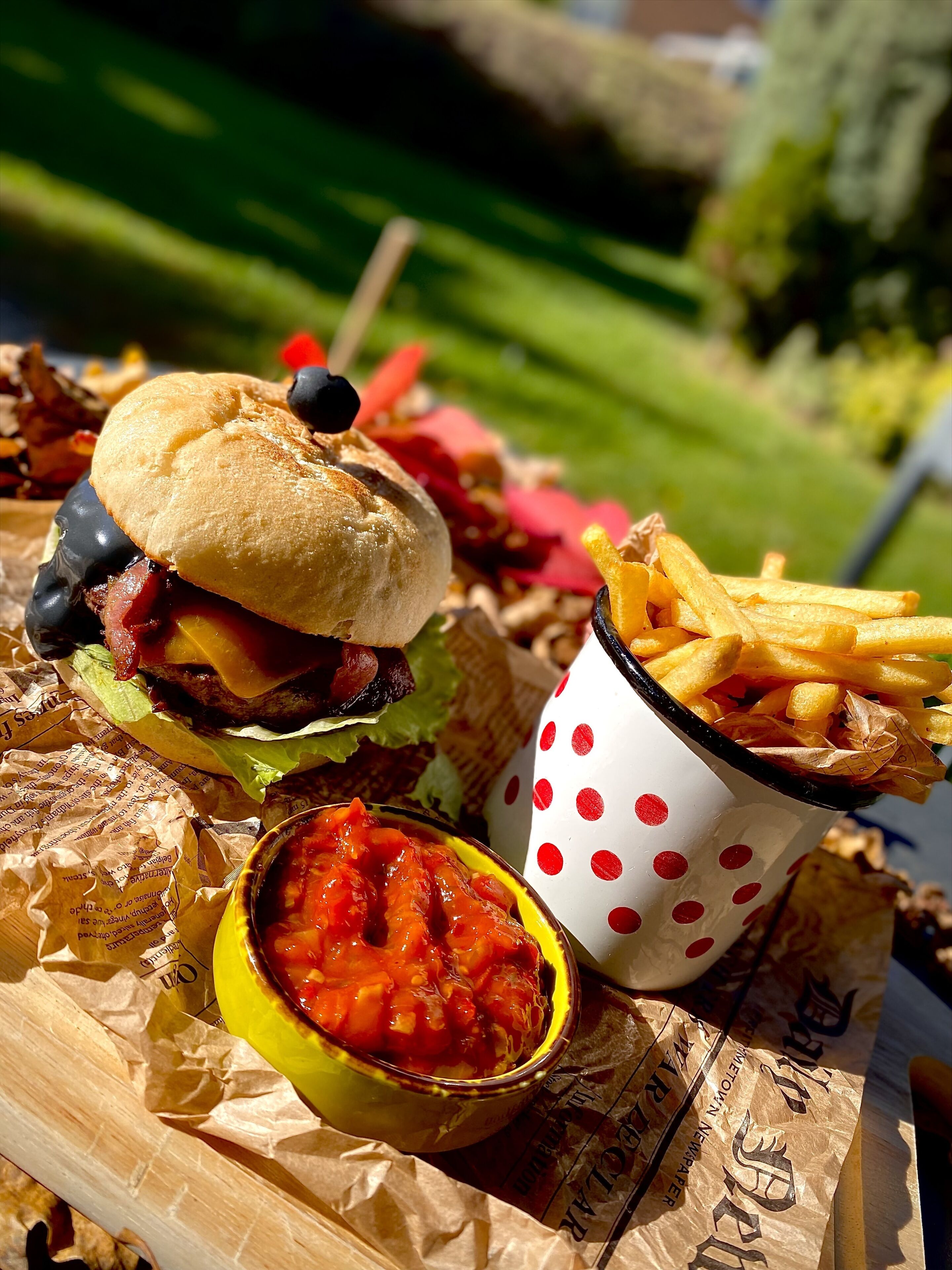 A meal consisting of a burger, fries, and a side of salsa.