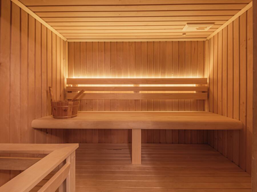 A wooden sauna with benches and a bench with a bucket.