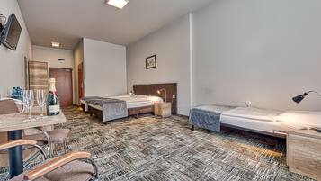 Ett hotellrum med två sängar, ett skrivbord med en stol, en tv som är monterad på väggen och en minibar.