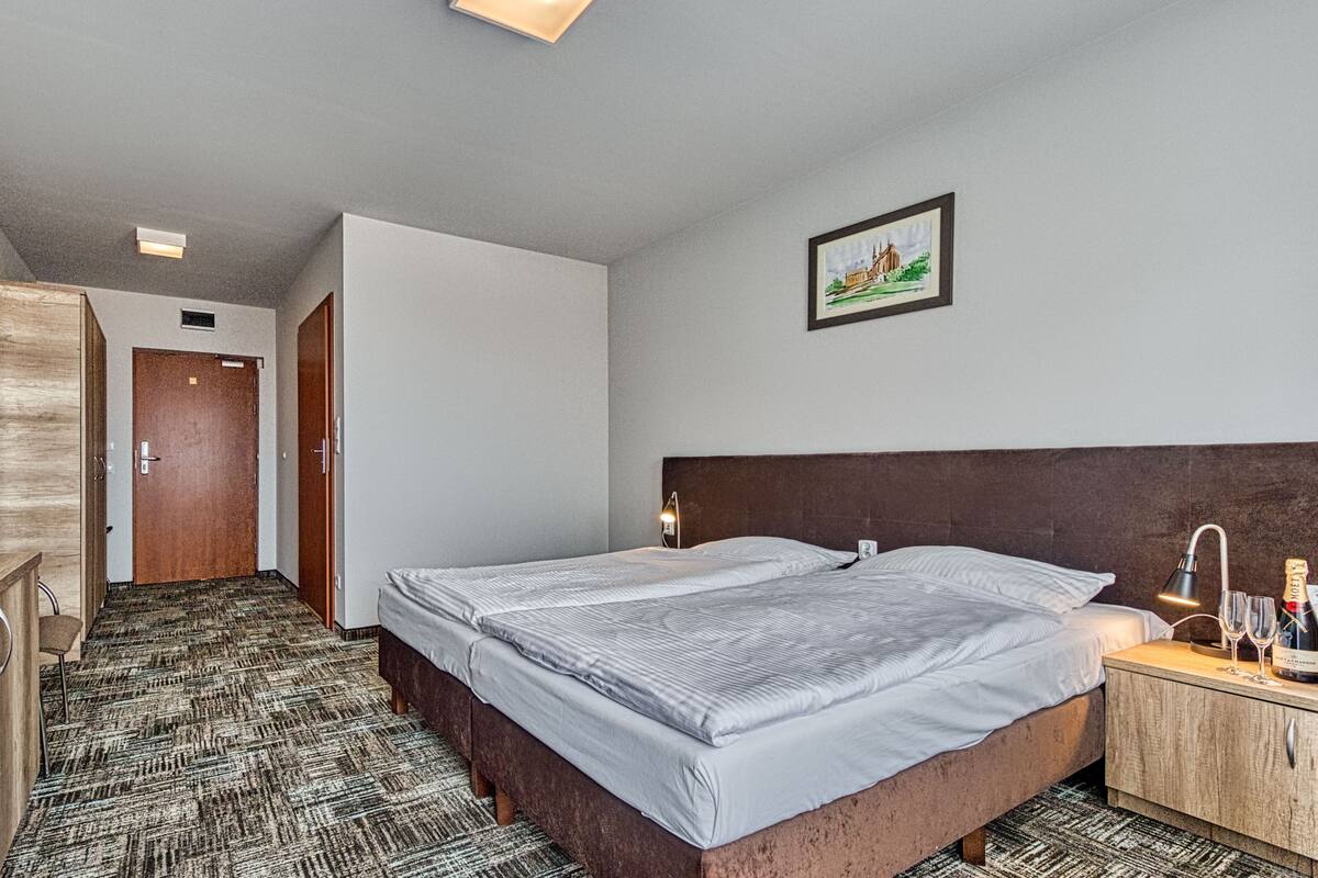 A hotel room with a bed, bedside table, and a picture on the wall.