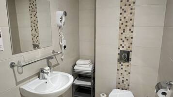 Un baño con lavamanos, espejo, inodoro y ducha.