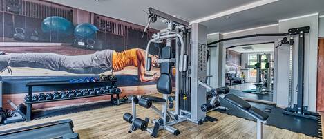 Ein Fitnessraum mit Trainingsgeräten, Wandmalerei und Laufband.