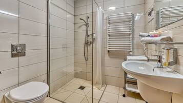 Un baño moderno con inodoro, lavamanos, ducha y un perchero para toallas.