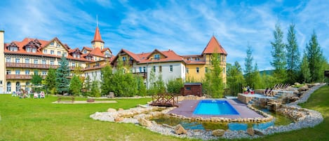 Un hotel con varias edificaciones, piscina y un pequeño estanque.
