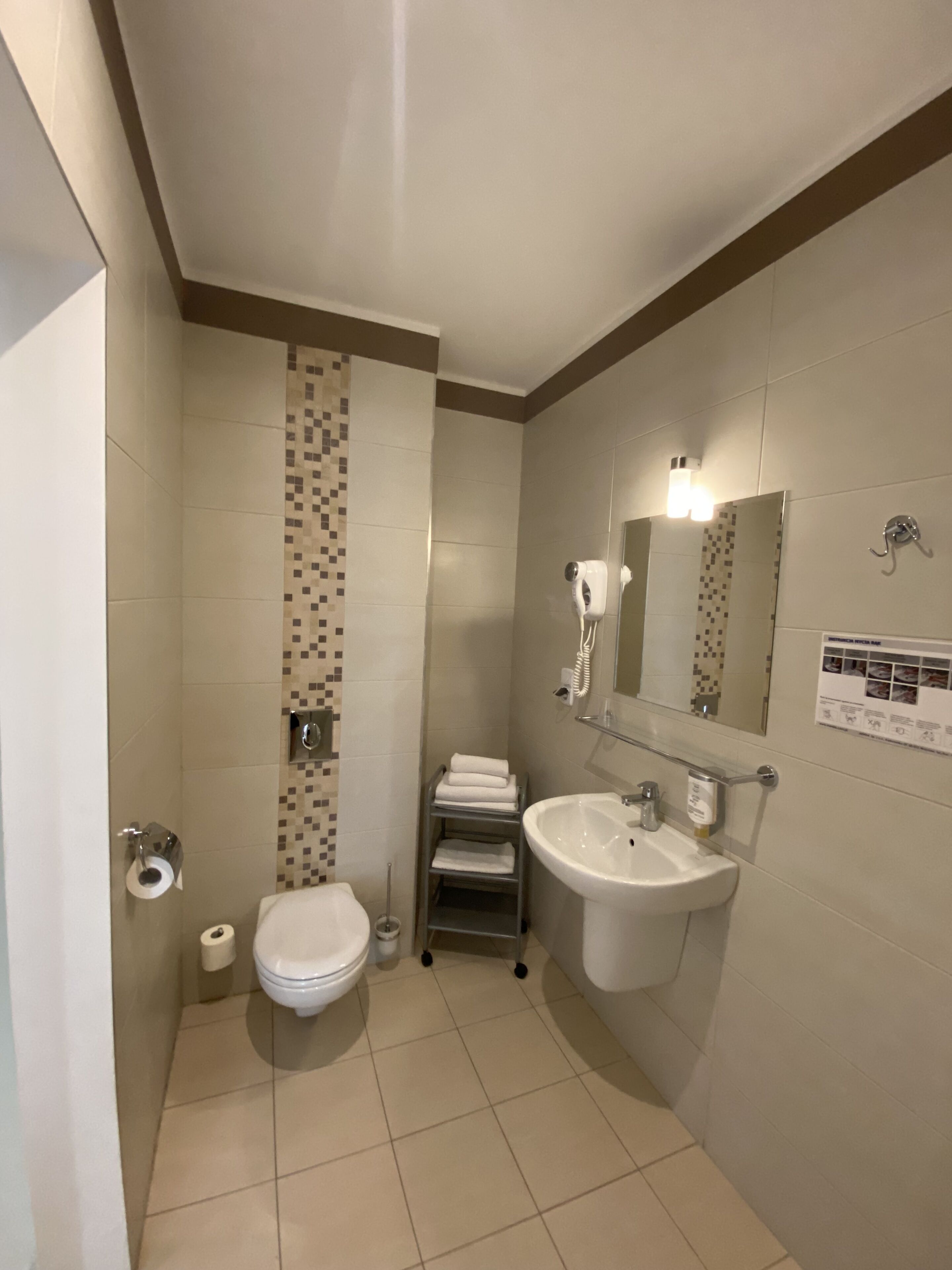 Uma casa de banho compacta com sanita, lavatório e suporte para toalhas.