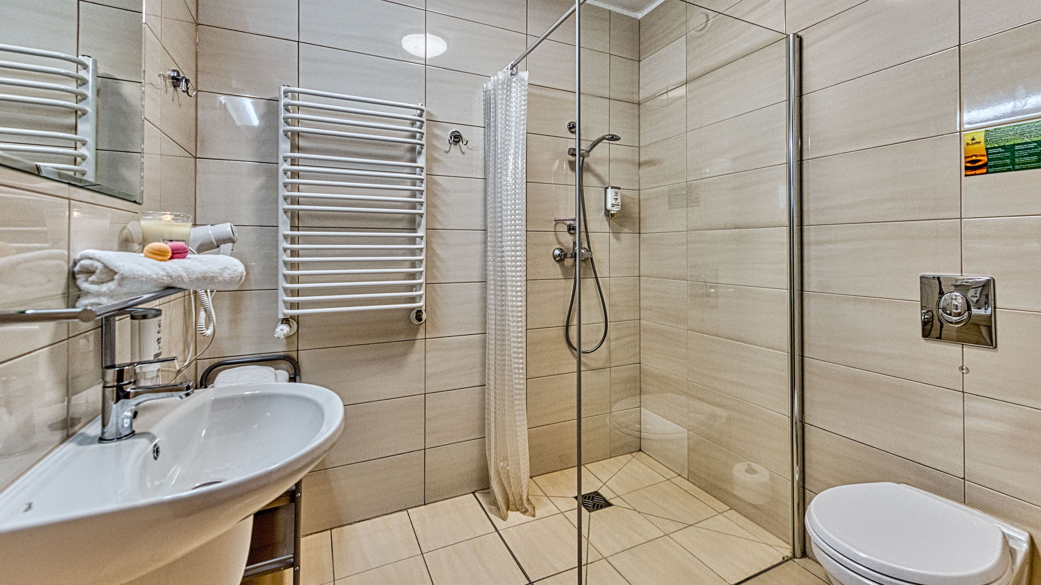 Une salle de bain équipée d’un lavabo, d’un miroir, d’un porte-serviettes, d’une douche et de toilettes.