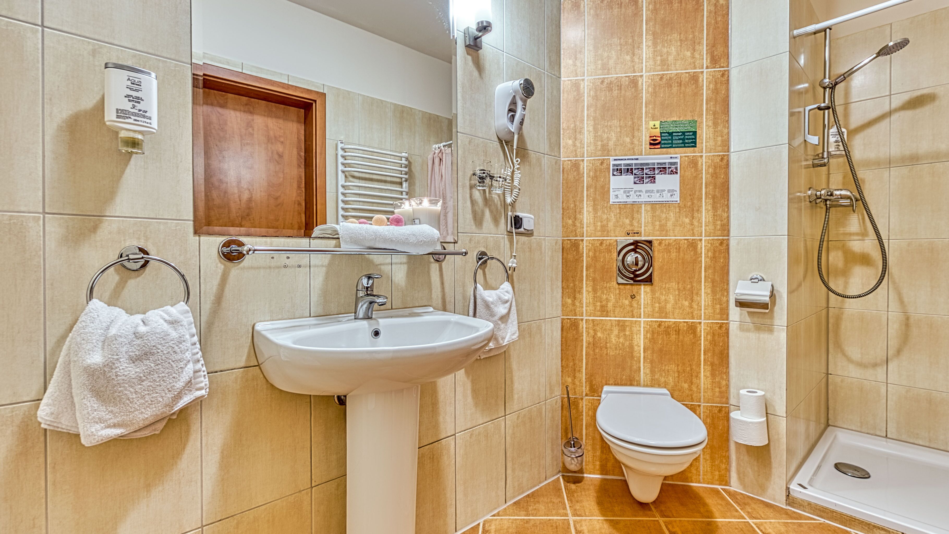 A bathroom with a sink, toilet, and shower. There are towels and toiletries on the sink area.
