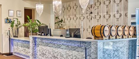 A reception area with marble counters, a computer, a plant, and decorative wooden barrels.